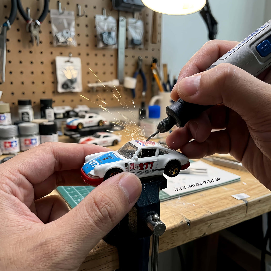 Makoauto workshop cutting a die-cast toy car to create a custom car charm.