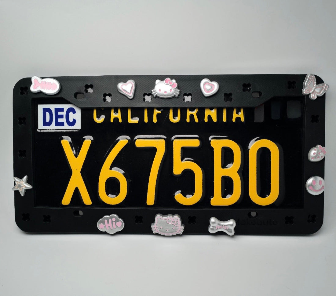 Full view of a black MAKOAUTO license plate frame styled with Hello Kitty shoe charms