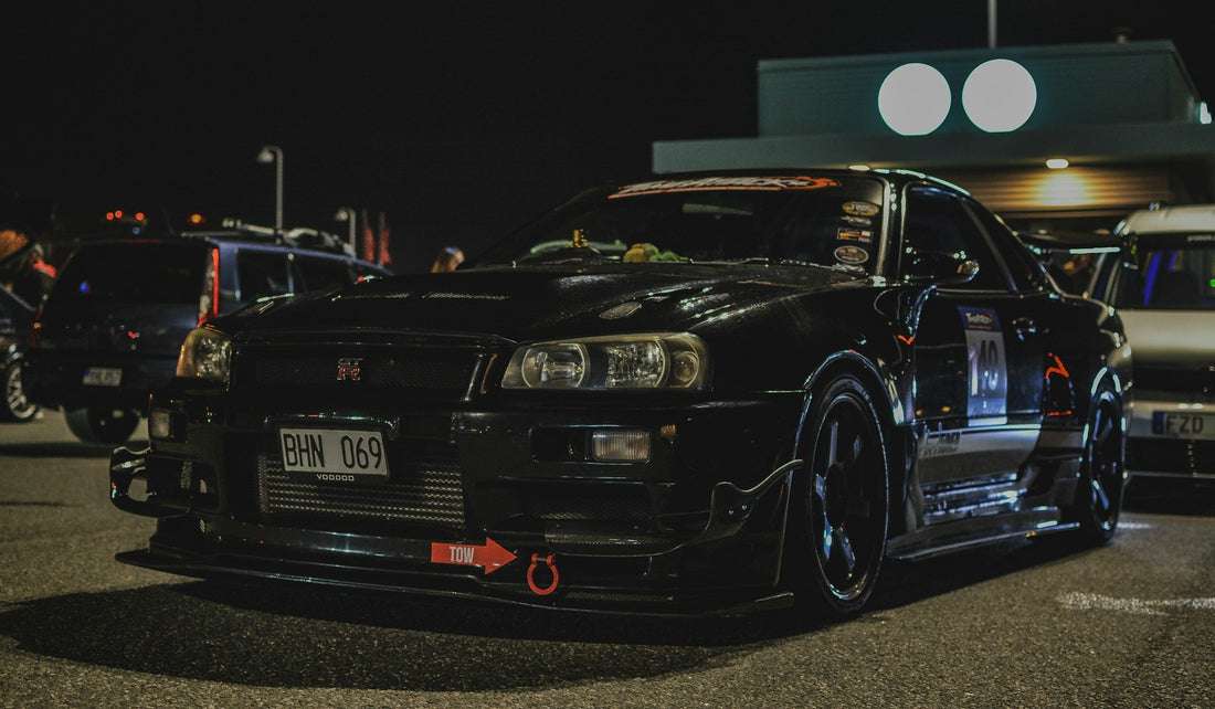 Modified black Japanese sports car parked at night before a car meet