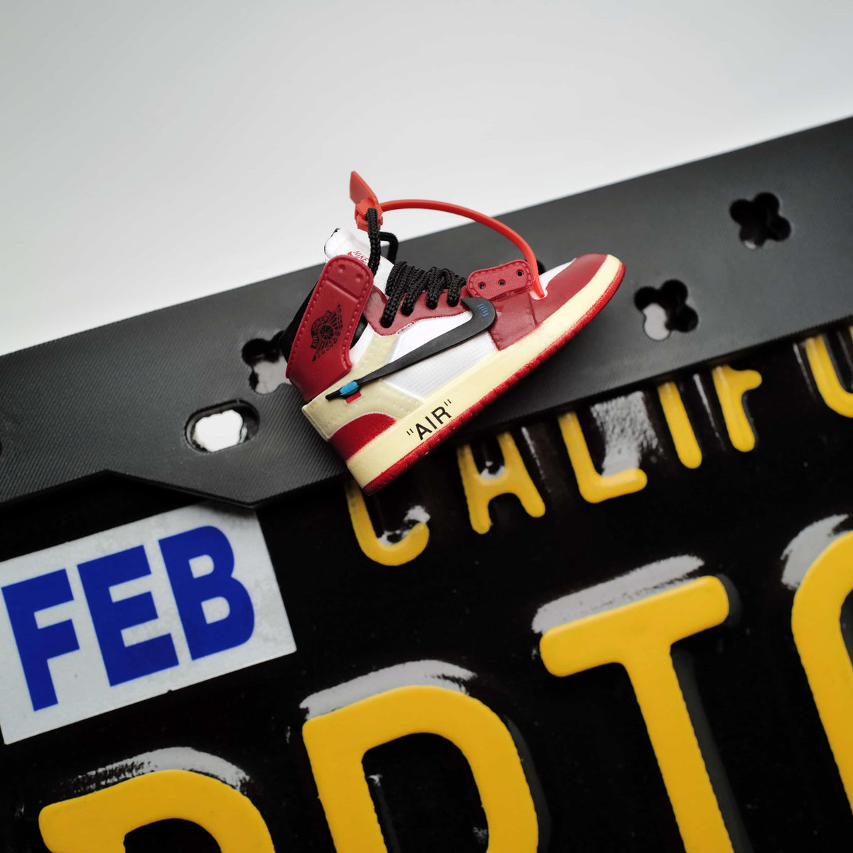 Close-up detail of a highly textured 3D streetwear sneaker charm securely snapped into the flexible Makoauto license plate cover