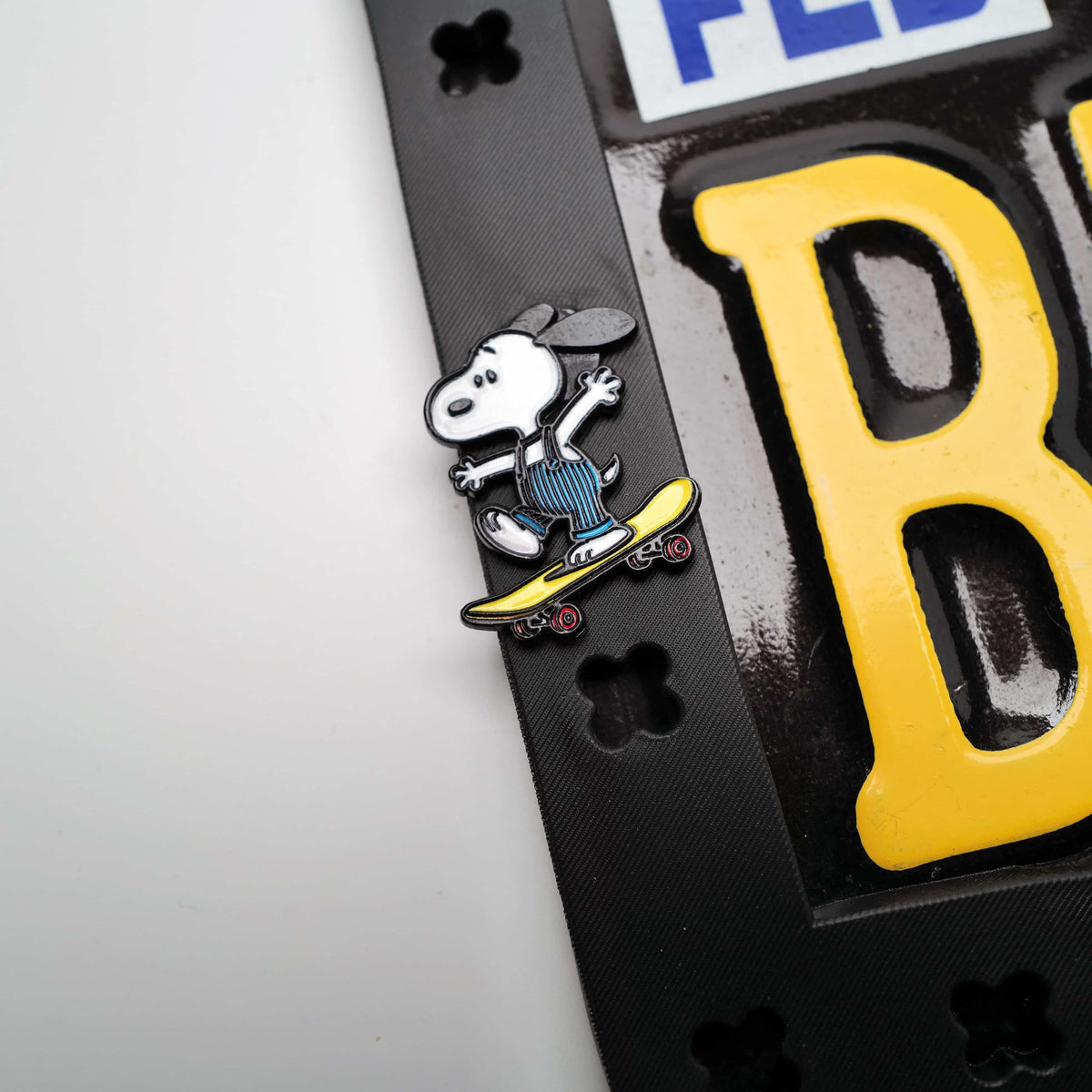 Detailed view of a cute cartoon skateboard dog figure attached to a flexible black license plate holder designed to reduce rattle