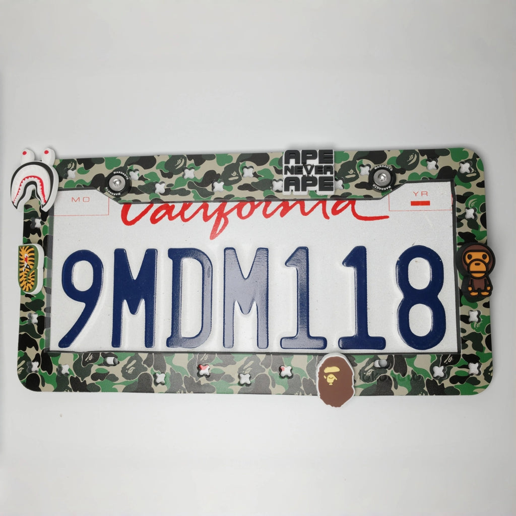 Full view of Makoauto classic green camo UV printed license plate frame with streetwear ape charms on a car