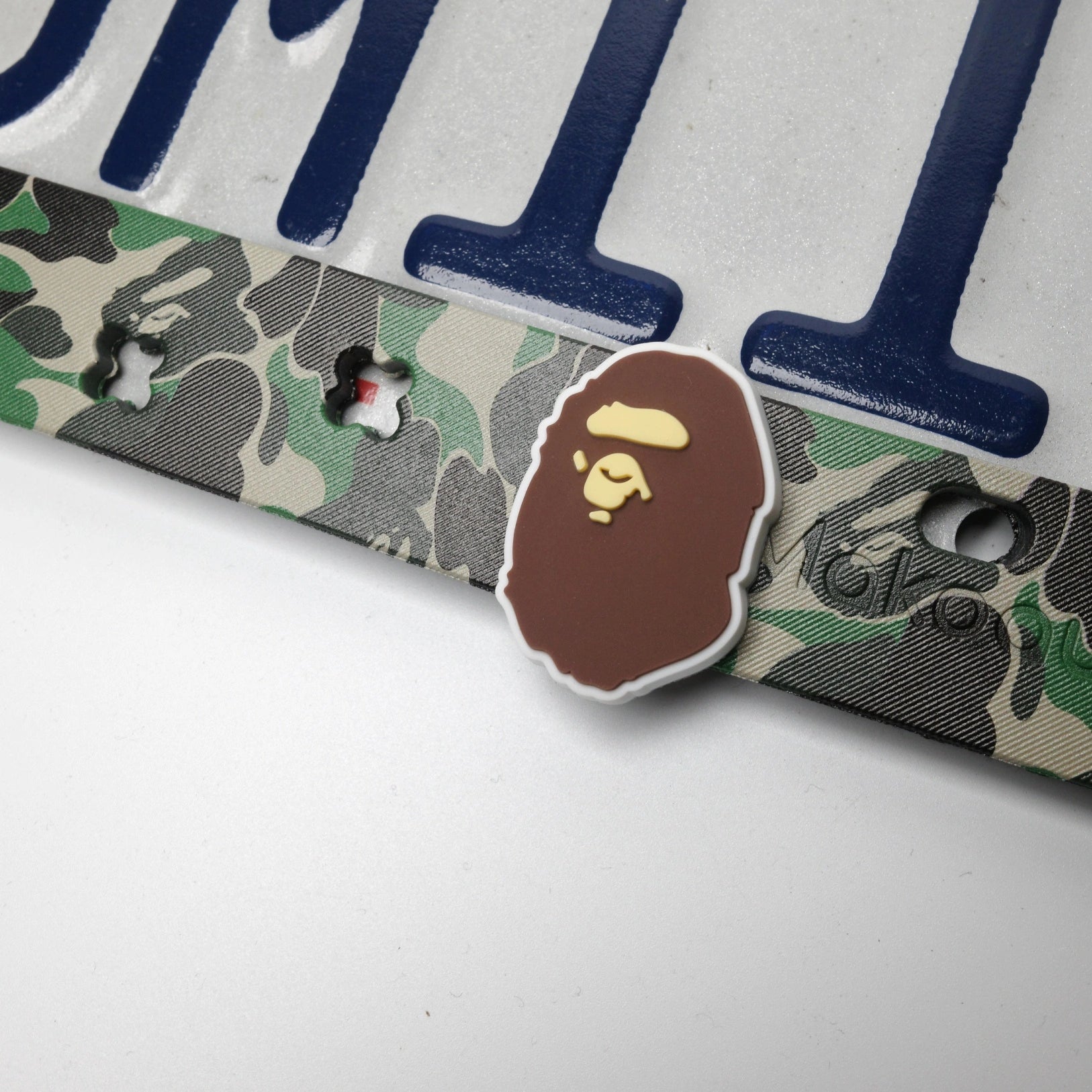 Macro detail shot of streetwear text UV printed on green camo license plate frame